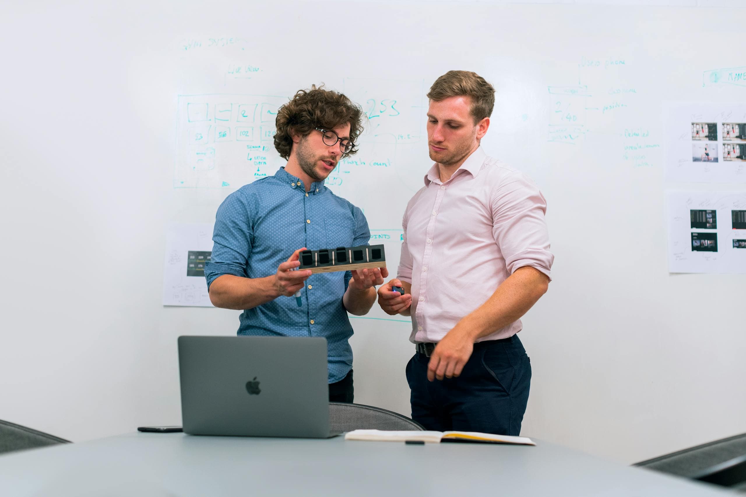 Two engineers reviewing a hardware prototype in a bright studio - laboratory R&D depth and credibility