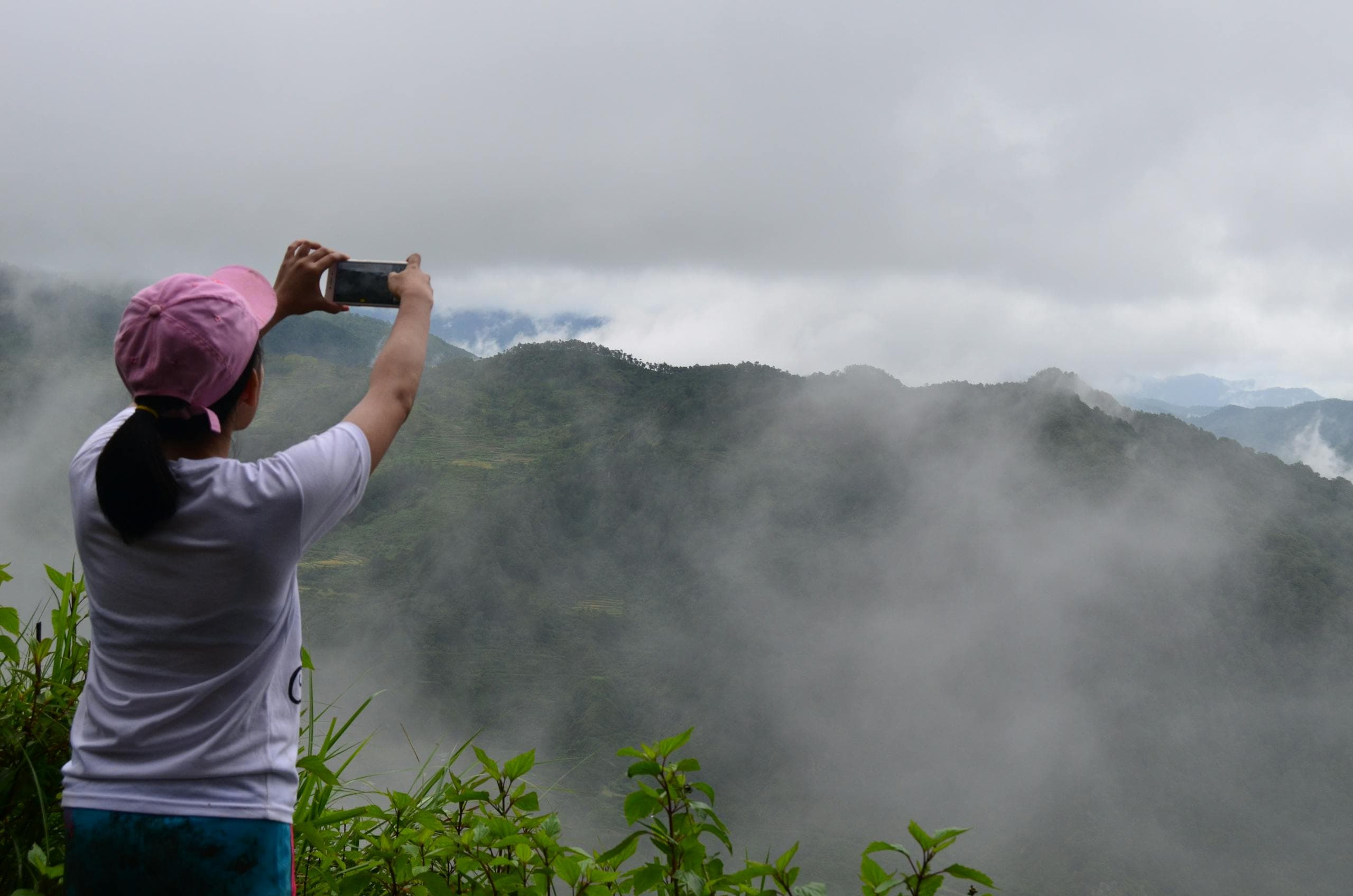 Person photographing misty mountains with a phone - pragmatic AI, clarity, and perception